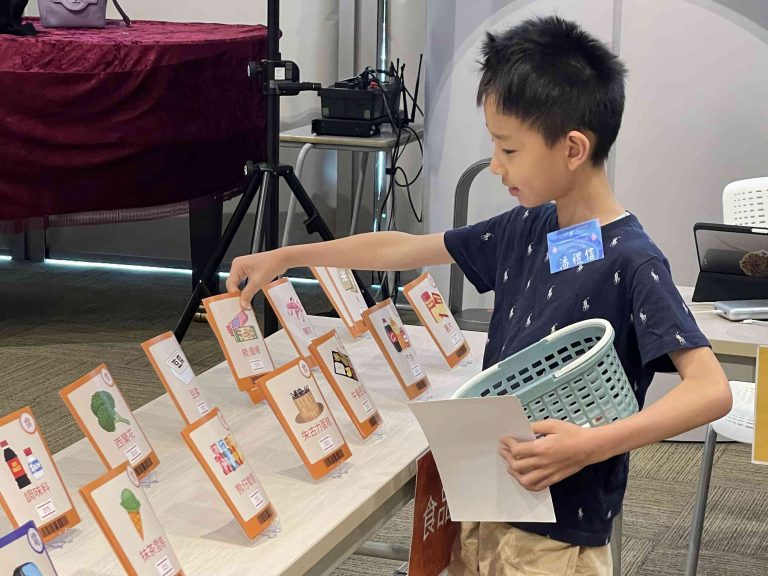 Participants engage in real-world financial decisions during social stimulation booth games. 

參加者透過攤位遊戲來賺取道具“金錢”，模擬社會經濟活動的實況。